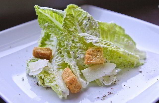 A Caesar salad with romaine hearts and croutons on a white plate
