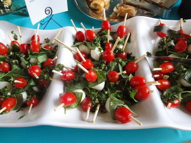 Caprese skewers with cherry tomatoes arranged on white platters