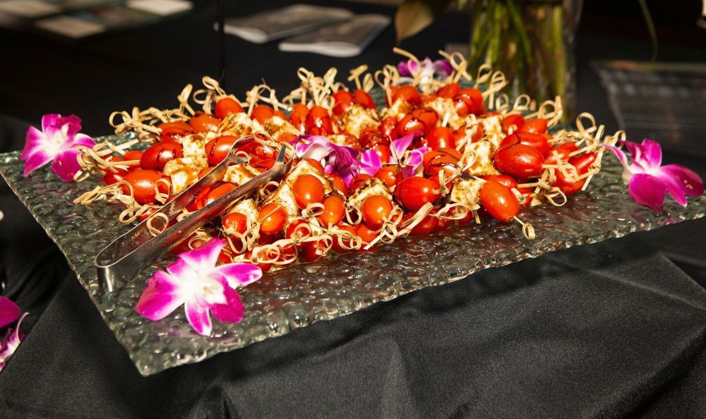 A 360 Catering appetizer platter with tomatoes and orchids on a dark tray